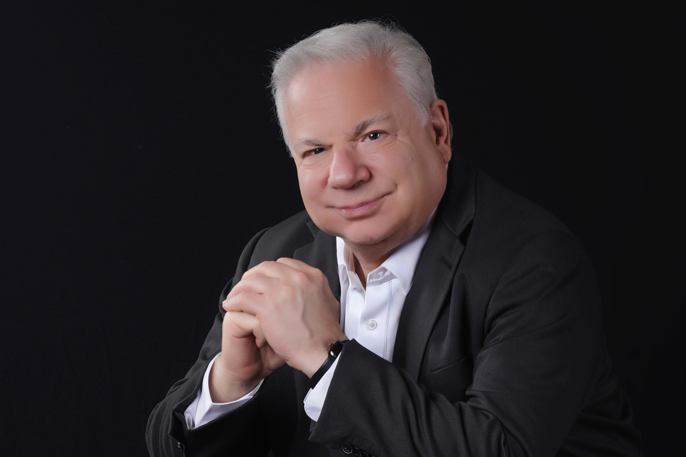 Mike Blinder in a black jacket against a dark studio background
